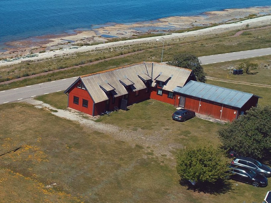 Lägenhetsbyggnaden i Byxelkrok sedd utifrån, röd träfasad vid kusten